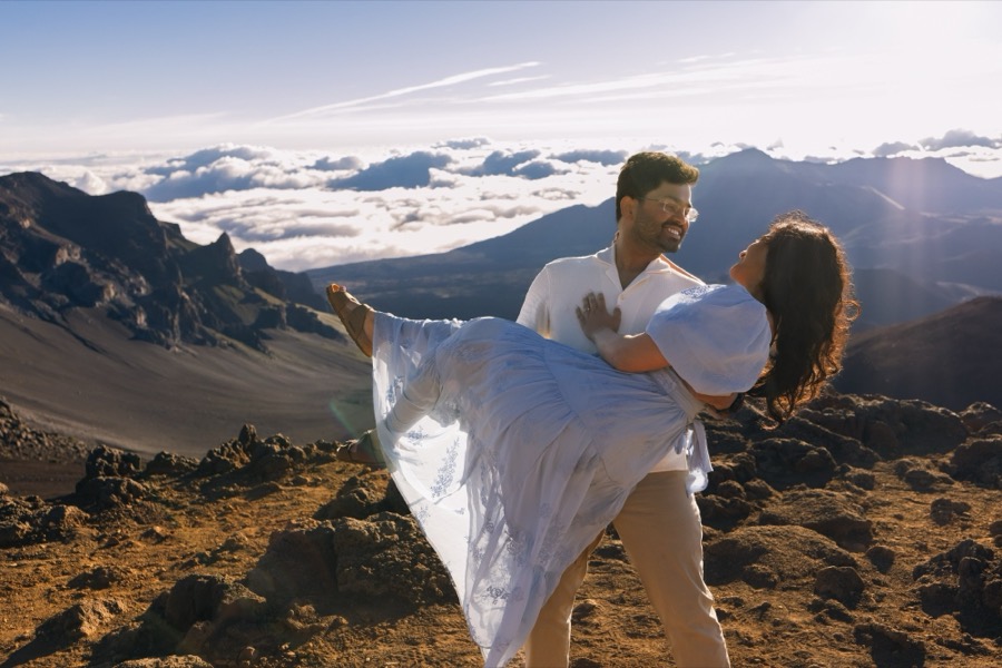 Aditya carrying Ankita, both laughing, above the clouds